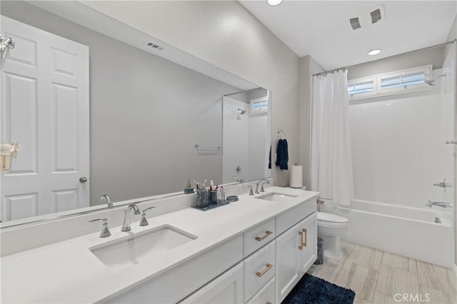 full bathroom with toilet, shower / bath combination with curtain, double vanity, and a sink