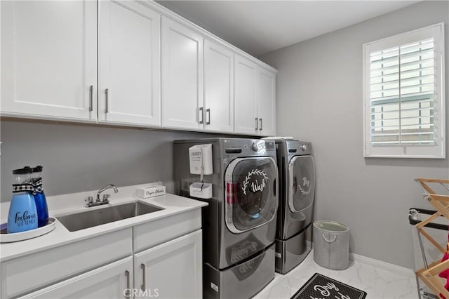 washroom with washing machine and dryer, a sink, baseboards, marble finish floor, and cabinet space