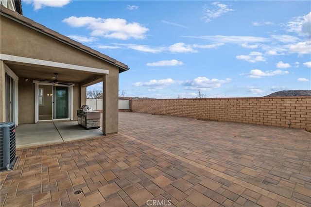 view of patio / terrace with a ceiling fan, fence, and central AC unit