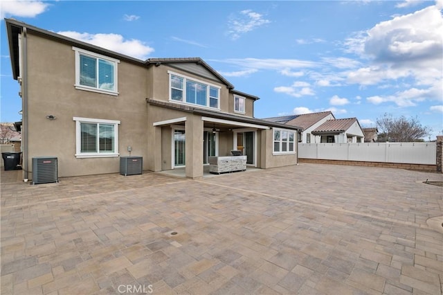 rear view of property with central AC, fence, a patio, and stucco siding