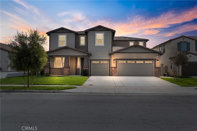 view of front of property with a garage, concrete driveway, stone siding, stucco siding, and a front yard