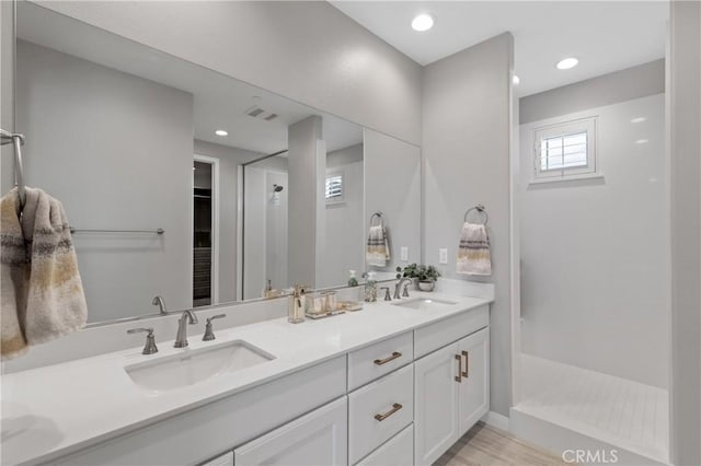 full bath featuring double vanity, visible vents, a sink, and a walk in shower