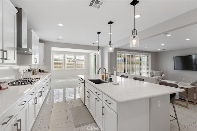 kitchen featuring stainless steel appliances, a sink, visible vents, wall chimney range hood, and plenty of natural light