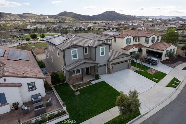 view of front of home with a tile roof, an attached garage, a mountain view, a residential view, and driveway