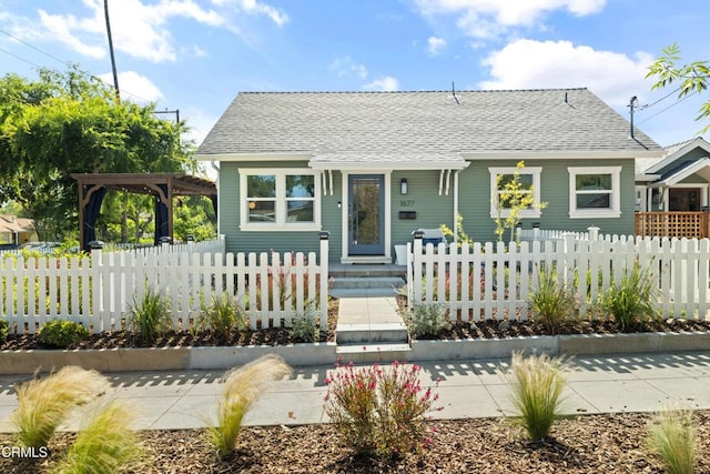 bungalow with a pergola, a fenced front yard, and a shingled roof