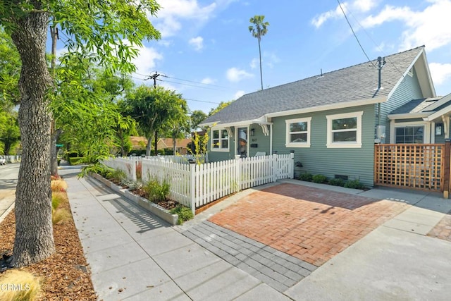 bungalow-style house with crawl space, a fenced front yard, and roof with shingles