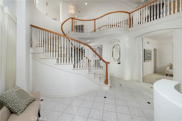 tiled entryway featuring a towering ceiling, stairs, a notable chandelier, and recessed lighting