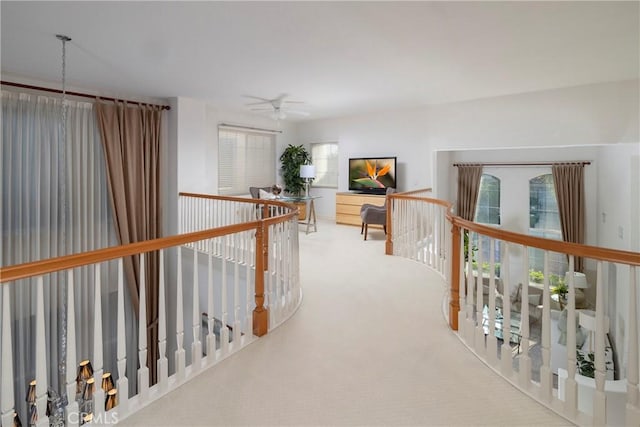 hall with carpet floors and an upstairs landing