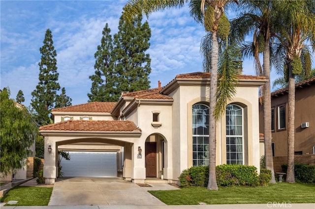 mediterranean / spanish home with concrete driveway, a tiled roof, a garage, and stucco siding