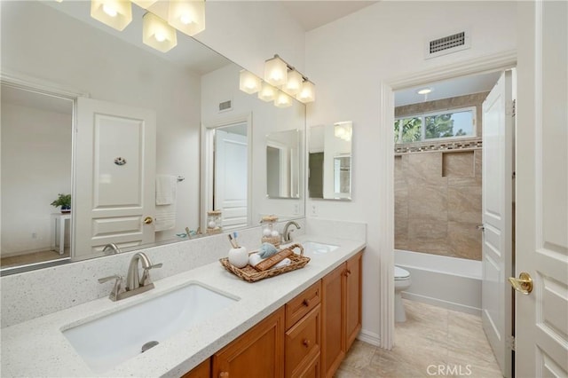 bathroom featuring toilet, double vanity, a sink, and visible vents