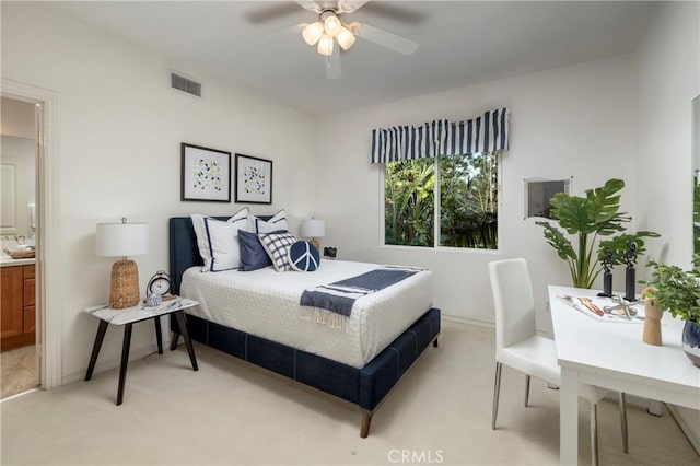 bedroom with visible vents, ensuite bathroom, a ceiling fan, and light colored carpet