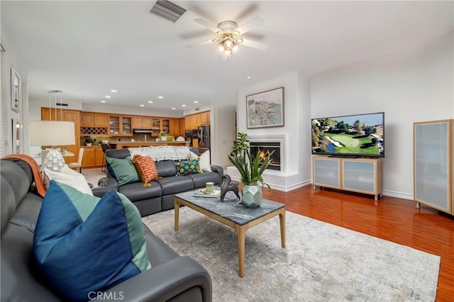 living area featuring light wood-style floors, recessed lighting, visible vents, and a glass covered fireplace