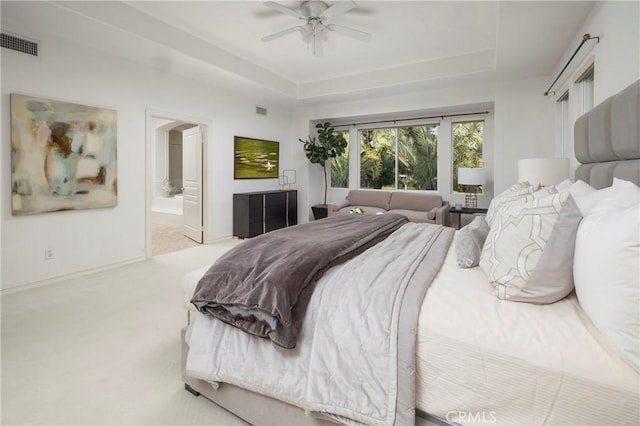 carpeted bedroom with baseboards, a raised ceiling, visible vents, and connected bathroom