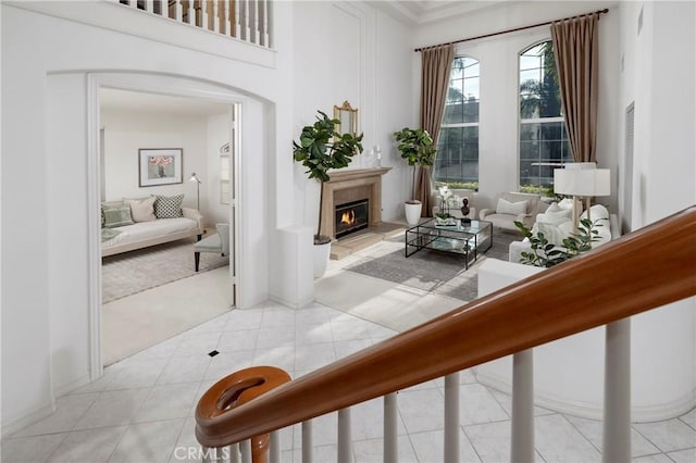 living area with a glass covered fireplace, light tile patterned flooring, and arched walkways