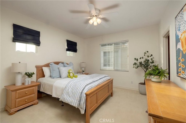 bedroom with a ceiling fan, light colored carpet, and baseboards