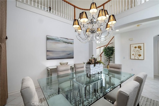 dining area with a notable chandelier, a towering ceiling, baseboards, and tile patterned floors