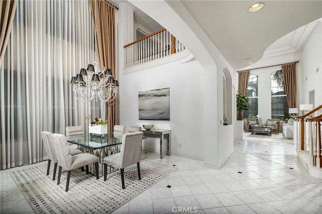 tiled dining room featuring arched walkways, recessed lighting, a high ceiling, a chandelier, and baseboards