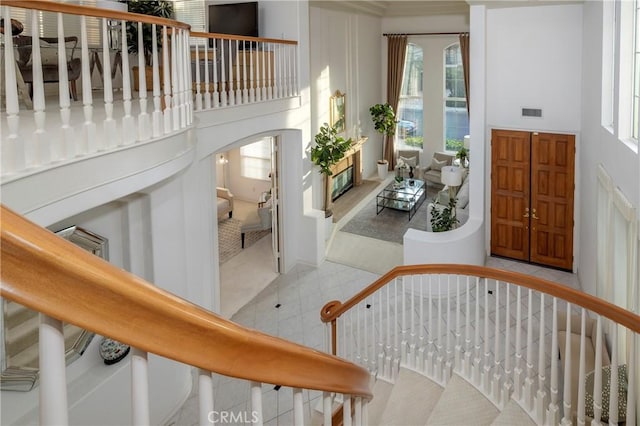 foyer featuring arched walkways, stairway, a high ceiling, and tile patterned floors