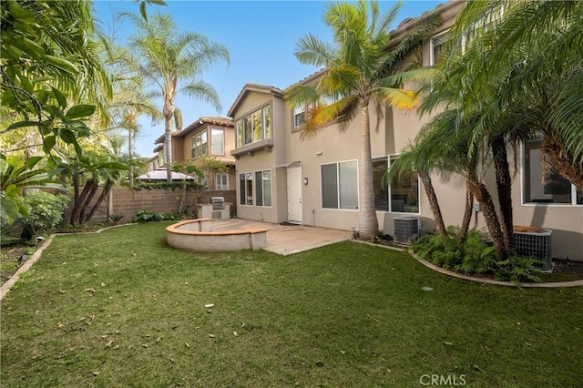 rear view of house featuring central air condition unit, fence, a yard, stucco siding, and a patio area