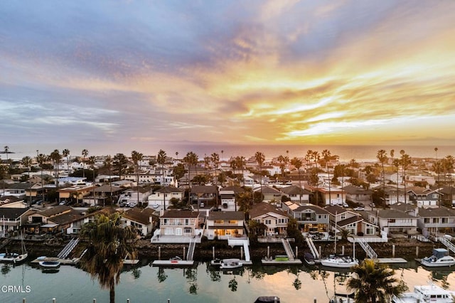 aerial view at dusk with a residential view and a water view