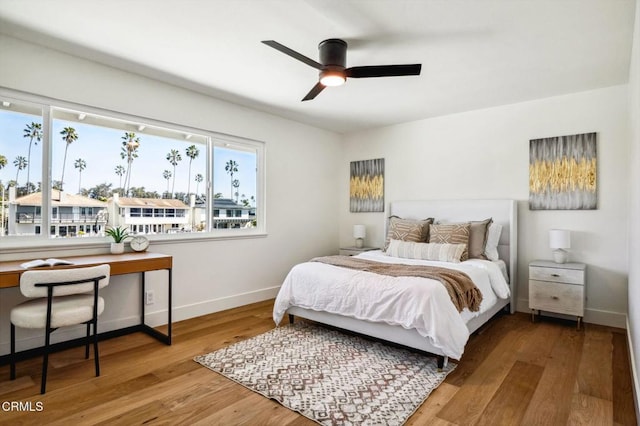 bedroom with a ceiling fan, baseboards, and wood finished floors