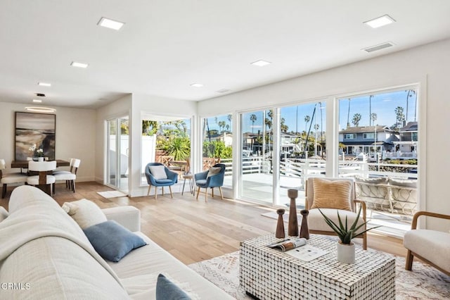 living room with visible vents, light wood-type flooring, and baseboards