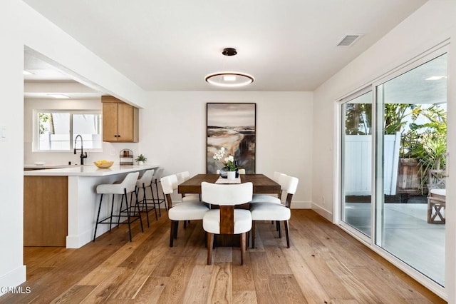 dining space featuring visible vents, light wood-style floors, baseboards, and a healthy amount of sunlight