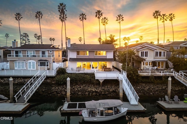 back of house at dusk featuring a water view