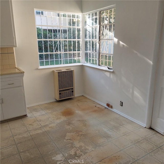 unfurnished dining area with baseboards and heating unit