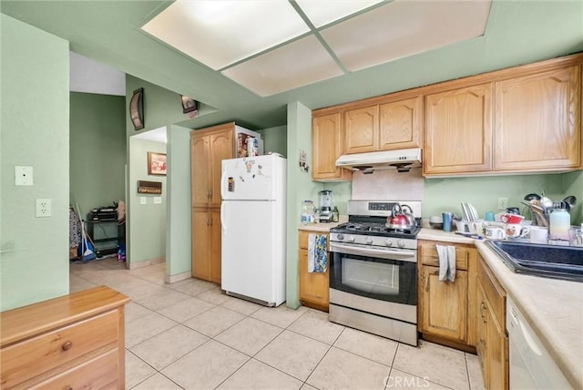 kitchen featuring light tile patterned floors, under cabinet range hood, white appliances, a sink, and light countertops