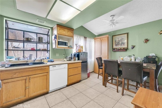 kitchen featuring stainless steel appliances, light countertops, vaulted ceiling, a sink, and ceiling fan