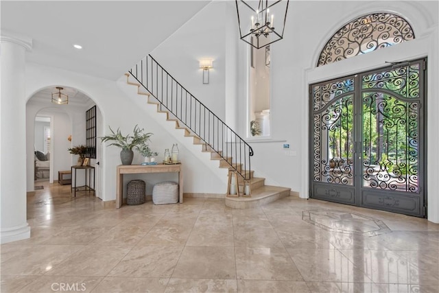 entrance foyer with baseboards, arched walkways, a high ceiling, stairs, and french doors