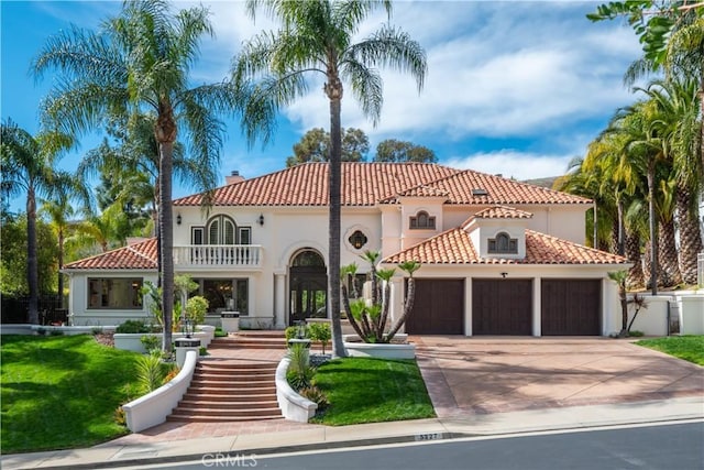 mediterranean / spanish home with stucco siding, concrete driveway, stairway, an attached garage, and a balcony