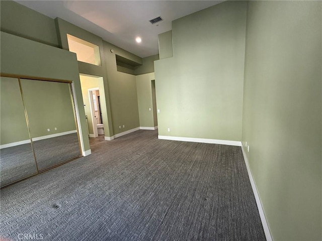 unfurnished bedroom featuring visible vents, carpet flooring, baseboards, and a towering ceiling