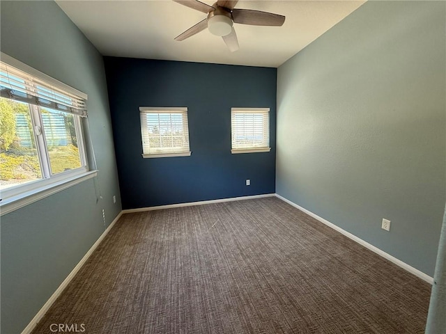 carpeted spare room featuring a ceiling fan and baseboards