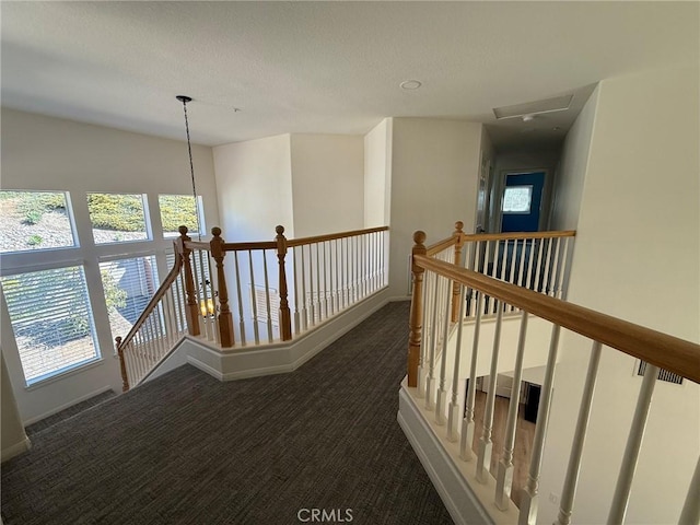 hall featuring an upstairs landing, baseboards, and carpet floors