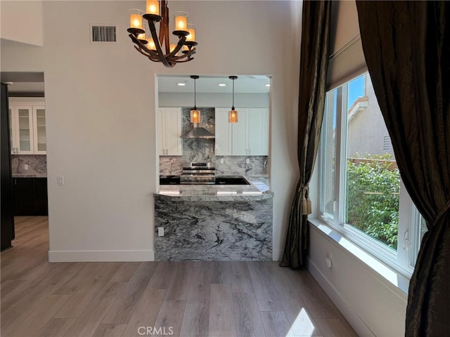 dining area featuring wood finished floors, visible vents, a chandelier, and baseboards