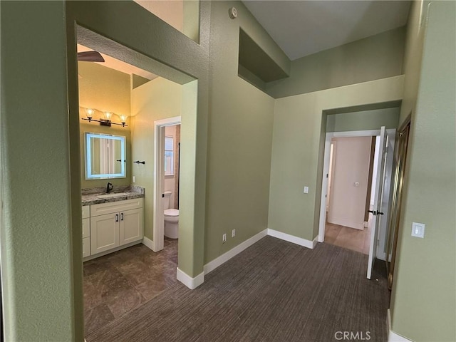 bathroom featuring toilet, vanity, and baseboards