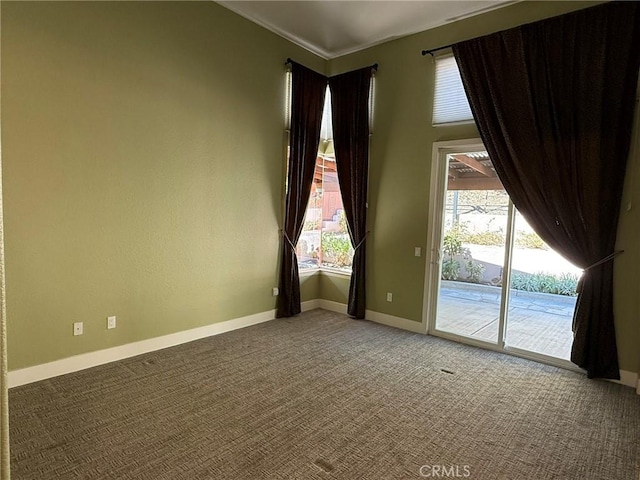 spare room with baseboards, plenty of natural light, and carpet