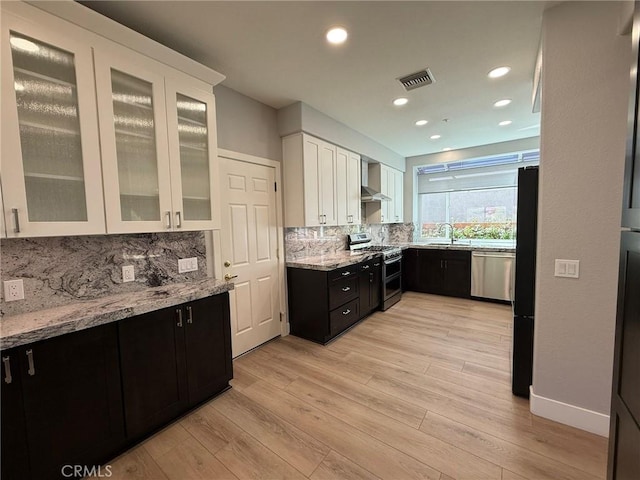 kitchen featuring visible vents, a sink, decorative backsplash, white cabinets, and appliances with stainless steel finishes