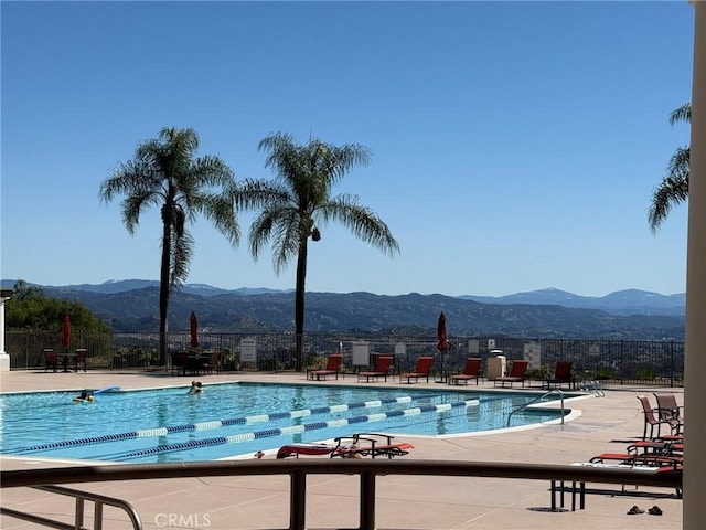 community pool featuring a mountain view, a patio, and fence