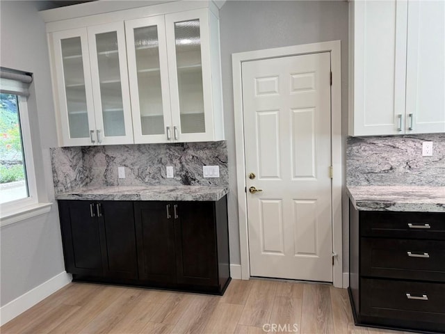 kitchen featuring white cabinets, glass insert cabinets, and light wood-type flooring