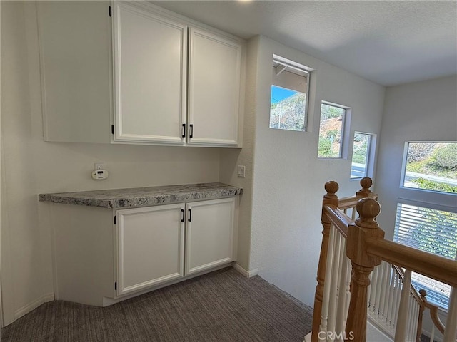 interior space featuring an upstairs landing and dark carpet