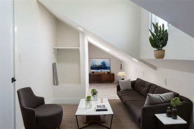 living area featuring baseboards, wood finished floors, and vaulted ceiling