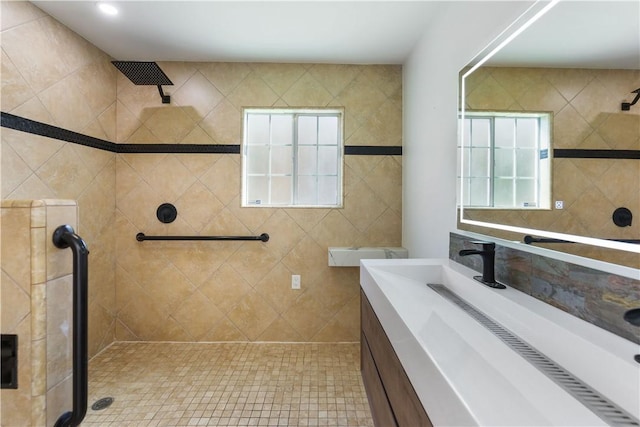 full bath featuring a tile shower, plenty of natural light, and vanity