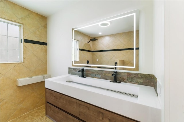 full bathroom featuring tile walls, tile patterned flooring, tiled shower, a healthy amount of sunlight, and vanity