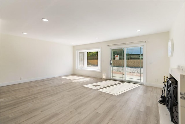 unfurnished living room with recessed lighting, a fireplace, baseboards, and light wood-style floors