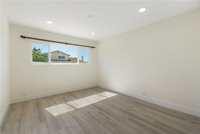 spare room featuring recessed lighting, wood finished floors, and baseboards