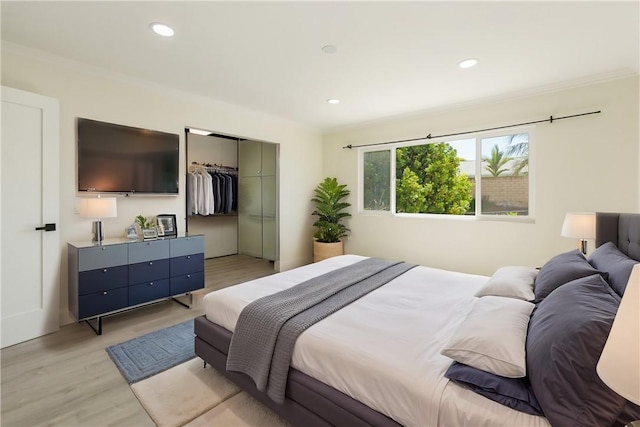 bedroom featuring a closet, recessed lighting, light wood-type flooring, and ornamental molding