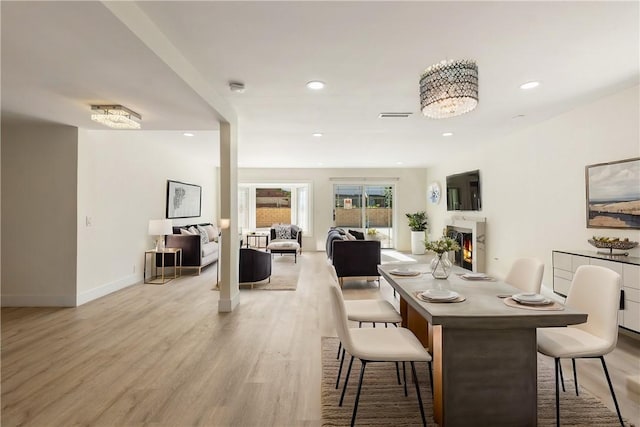 dining area with recessed lighting, visible vents, light wood finished floors, and a lit fireplace